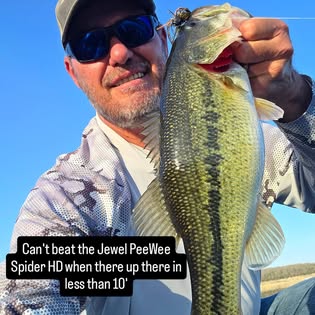 An angler holding a bass caught on a PeeWee Spider HD jig